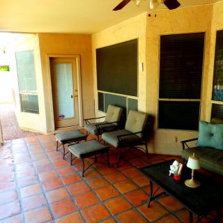 A cozy patio area with terracotta tile flooring, featuring comfortable seating and a ceiling fan for relaxation.
