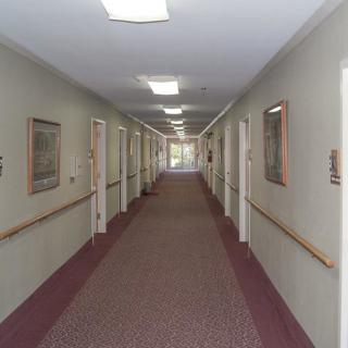 A long, carpeted hallway with doors on either side and ceiling lights.