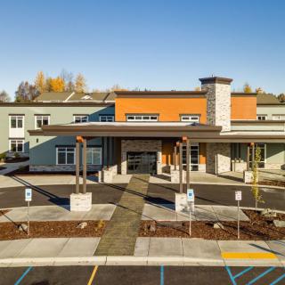 A modern building with a central entrance and adjacent parking area.