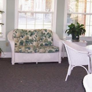 A cozy living space featuring a floral-patterned sofa, accompanied by a plant and a dining table.