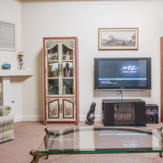 A cozy living room setup featuring a television, glass coffee table, and decorated cabinet.