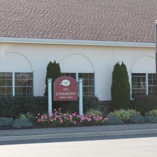 The exterior of a building featuring a welcoming sign and landscaped flower beds.