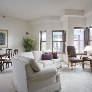 A cozy and elegant living room with a sofa, chairs, and dining area.