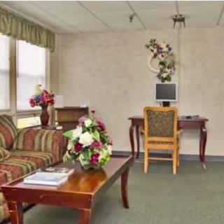A cozy living room featuring a striped sofa, a wooden coffee table with floral arrangements, and a computer desk in the corner.