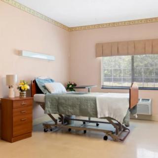 A tidy hospital room featuring a single patient bed with natural light streaming in through the window.