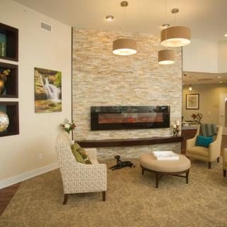 A modern living room with a cozy seating area in front of a sleek fireplace, complemented by stylish decor and artwork.