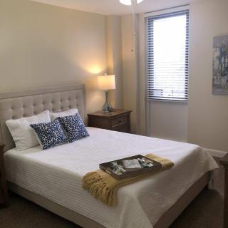 A cozy bedroom with a neatly made bed, stylish pillows, and soft lighting.