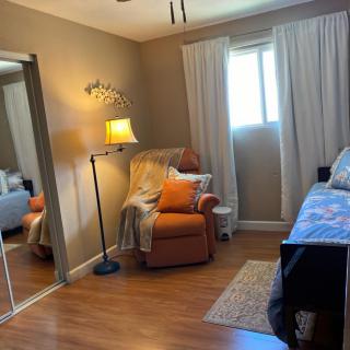 A cozy bedroom with a comfortable chair, bed, and a standing lamp near the window.