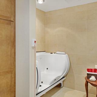A modern bathroom featuring a walk-in bathtub with beige tiled walls.
