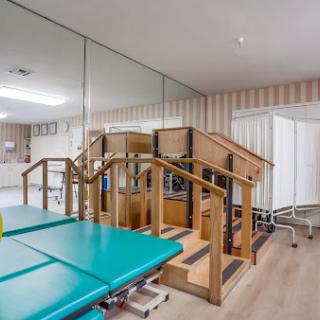 A well-equipped rehabilitation therapy room featuring a set of stairs and treatment tables.