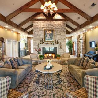 A warm and inviting living room with a traditional design, featuring a vaulted ceiling, stone fireplace, and elegant chandelier.