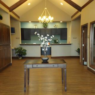 A modern interior with a central table, chandelier, and plants.