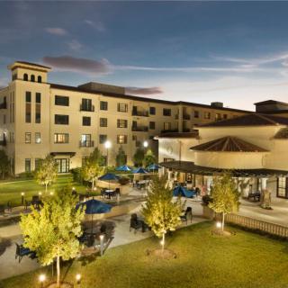 A beautifully lit hotel with outdoor seating and landscaped gardens at night.