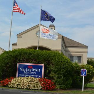 Entrance of the Spring Mill Manor with flags and a handicap parking spot.