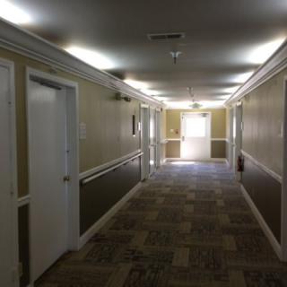 A well-lit hallway with several doors and patterned carpeting.