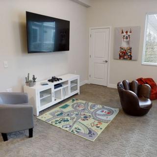 A cozy living room with a wall-mounted TV and children's play area.