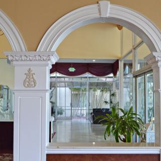 A hotel lobby featuring an ornate archway and indoor plants.