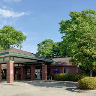 A welcoming building surrounded by greenery under a clear blue sky.