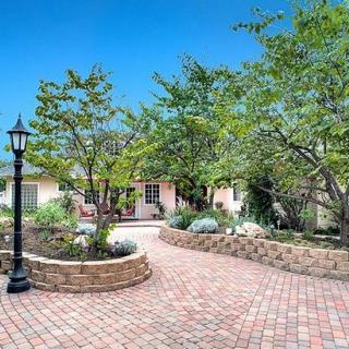 A charming house with a brick driveway and lush garden.