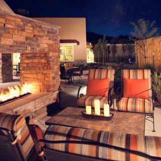 A cozy outdoor patio area with a lit fireplace and comfortable seating at night.