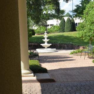 A serene garden pathway featuring a beautiful fountain and lush greenery.