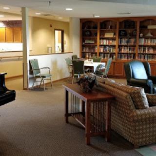 A cozy lounge area featuring comfortable seating and a bookshelf, ideal for relaxation and socialization.