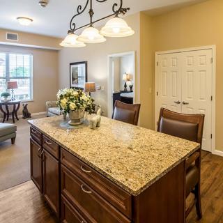 A modern kitchen featuring a granite-topped island and warm wood furnishings.
