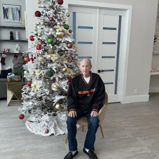 A person seated near a beautifully decorated Christmas tree.