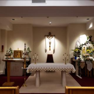 A church altar with a crucifix, adorned with flowers and candles.