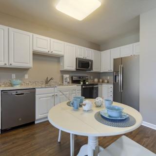 A modern kitchen with white cabinets and a small dining table set under bright lighting.