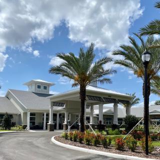A scenic view of a modern building surrounded by palm trees under a partly cloudy sky.