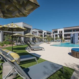 A sunny day at a modern resort with a pool and sun loungers.