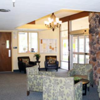 A cozy lobby area featuring upholstered chairs, a small table, and natural lighting from large windows.
