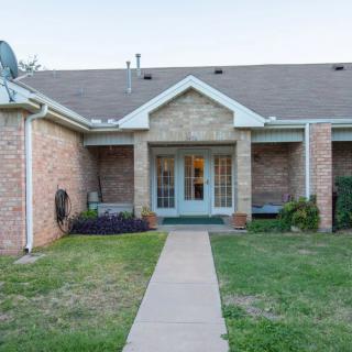 A brick house with a pathway leading to the entrance and a front yard.