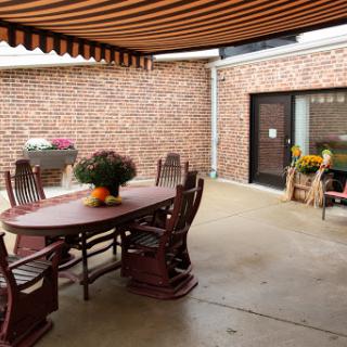 A cozy outdoor patio area with a wooden table and rocking chairs, perfect for gatherings.