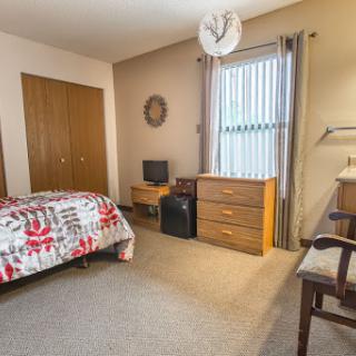 A cozy and well-furnished bedroom featuring a bed, dresser, and study desk.