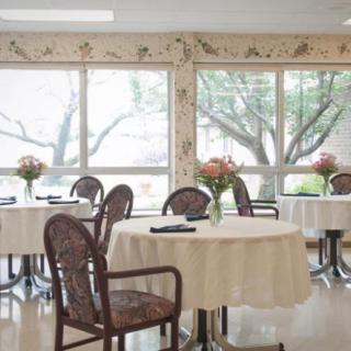 A bright dining room with neatly arranged tables and chairs, adorned with floral decorations.