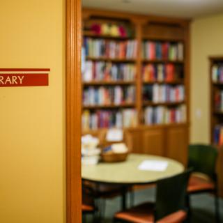 A cozy library room with shelves full of books and a round table with chairs.
