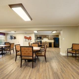 A modern dining area with wooden flooring and seating arrangement, adjacent to a kitchen space.