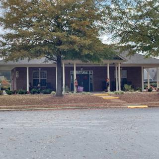 A small brick building surrounded by trees with a visible entrance.