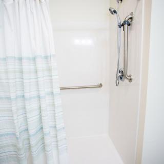 A modern shower with a striped curtain and grab bar.
