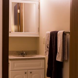 A bathroom with a vanity sink, mirror, and neatly hung towels.