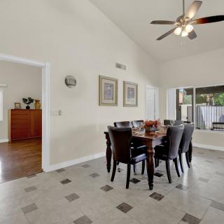 A spacious dining room with a round table, surrounded by chairs and illuminated by a ceiling fan.