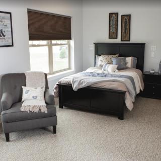 A cozy and neatly arranged bedroom with a bed, armchair, and window.