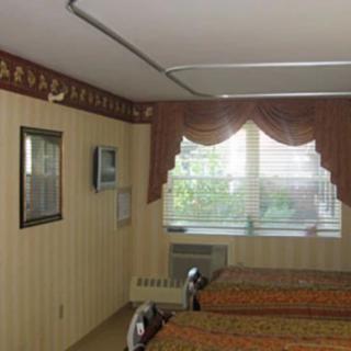 A hotel room with two beds, decorated with patterned wallpaper and curtains.