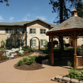 A serene garden view with a gazebo and a two-story building in the background.