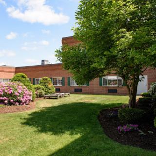 A serene garden with blooming flowers and a well-maintained lawn beside a brick building.