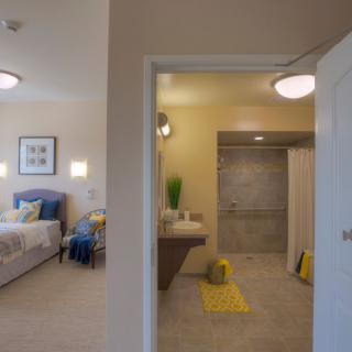 A modern bedroom and bathroom with elegant decor and lighting.