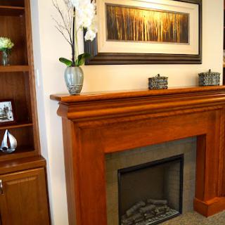 A beautifully designed living space featuring a wooden fireplace mantel, elegant artwork, and tasteful decorative accents.