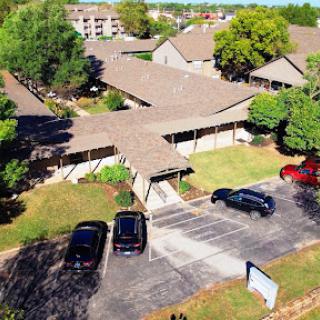 Aerial view of a residential complex with parking and surrounding greenery.